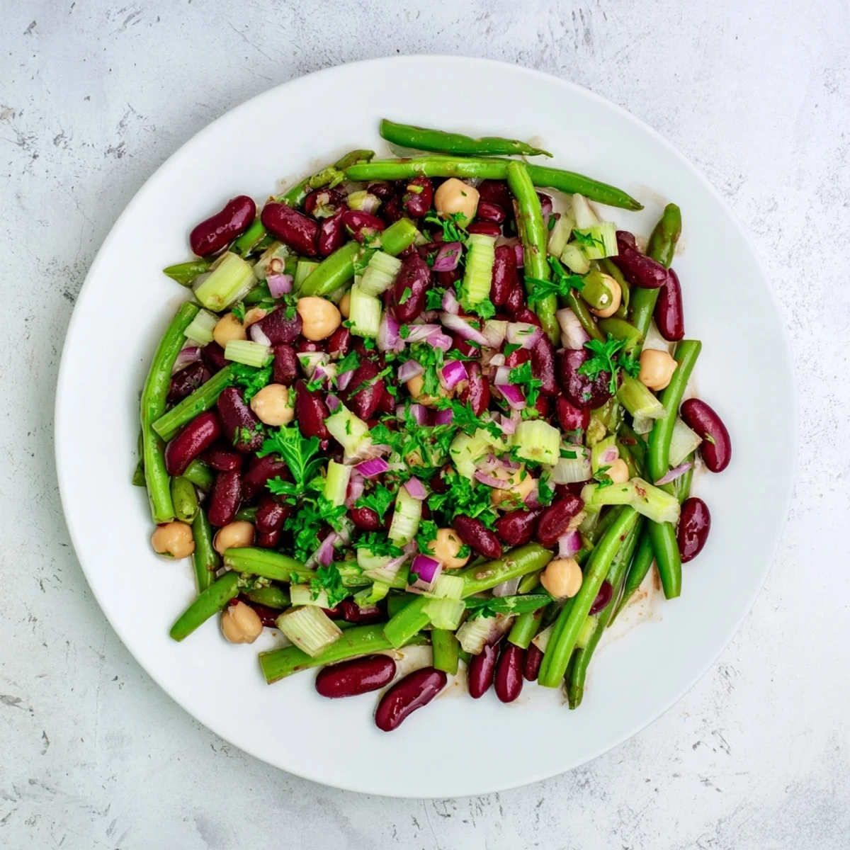 A vibrant bowl of Three-Bean Salad, brimming with green beans, kidney beans, and chickpeas in a tangy vinaigrette.