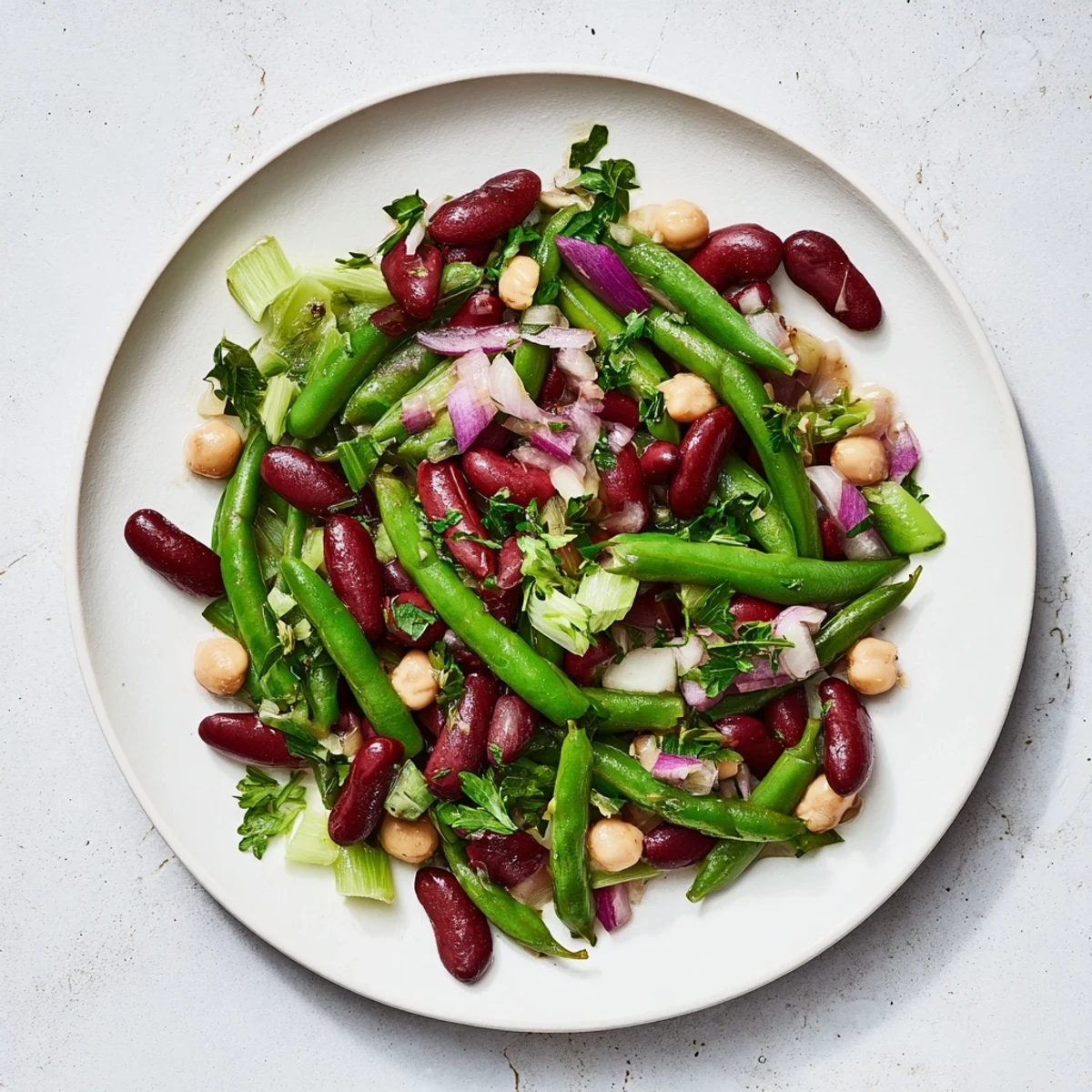 Hearty Three-Bean Salad with crisp celery, red onion, and fresh parsley, tossed in a bright apple cider vinegar dressing.