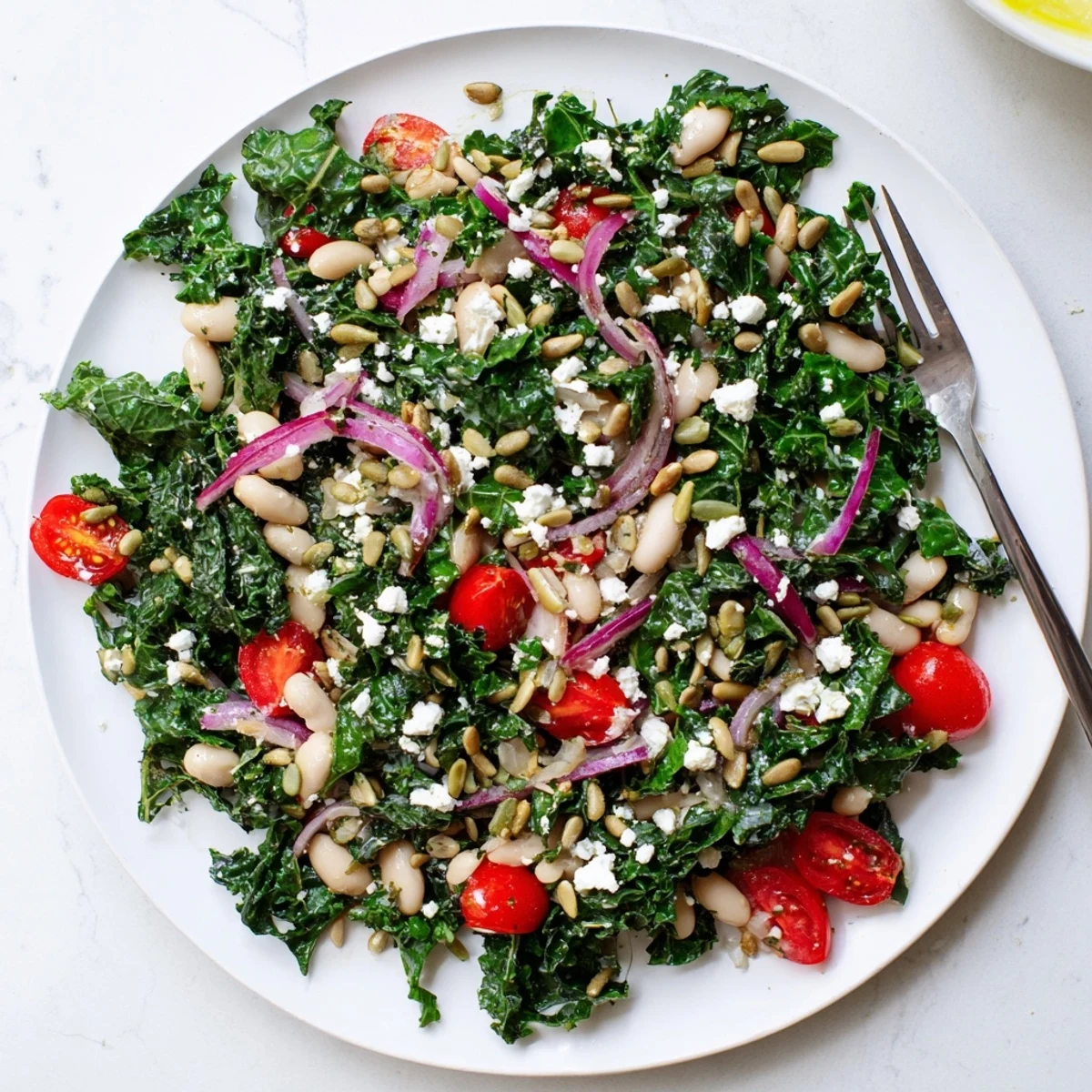 Enjoy a hearty White Bean and Kale Salad with tender kale, creamy beans, cherry tomatoes, and a zesty lemon dressing, topped with optional feta and seeds.