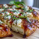 A close-up slice reveals drizzled spicy honey and fresh basil over the cheesy surface.