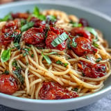 Pasta with cherry tomato confit, glistening in garlic oil, hints of basil.