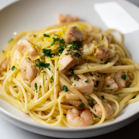 Tender chicken and succulent shrimp tossed in a zesty lemon garlic butter sauce over linguine for a vibrant surf-and-turf dinner.