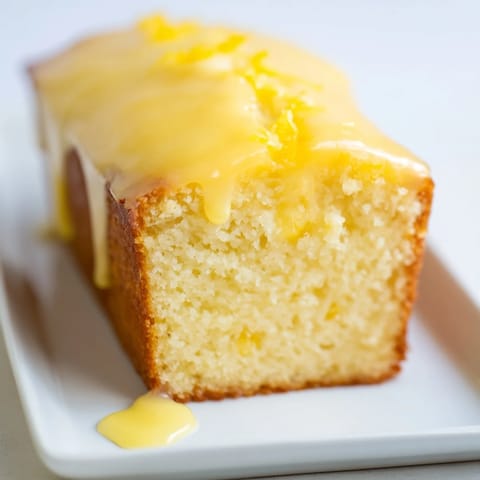 Close-up of a golden brown, freshly baked lemon loaf cake with bright lemon zest.
