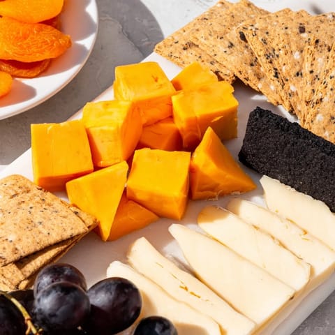 Dark cheeses and grapes create the haunting shape of the Halloween charcuterie board’s ghostly outline.