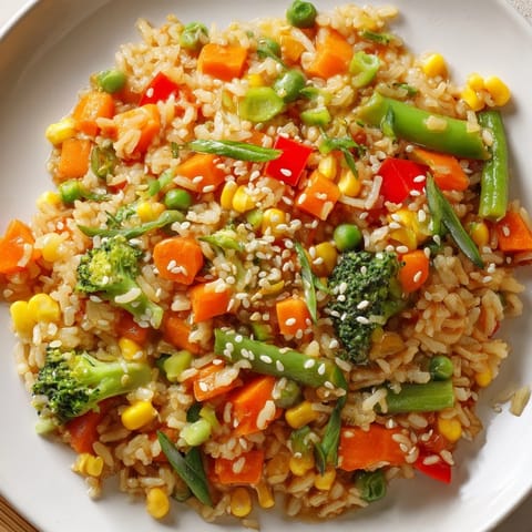 Savory homemade vegetable fried rice served in a white bowl, garnished with green onions and sesame seeds, ready for a quick dinner.