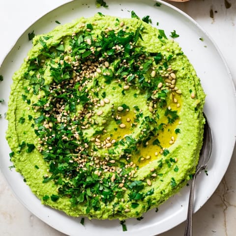 Creamy green Edamame Hummus served in a rustic bowl with pita chips and sliced cucumbers, perfect for a healthy snack.