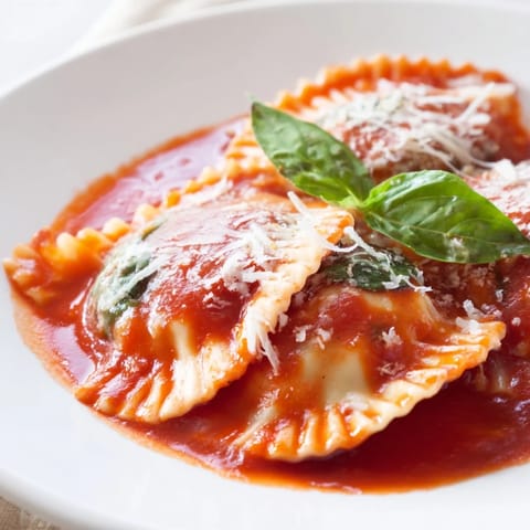 Steaming Spinach Ricotta Ravioli plated with marinara and basil, ready for a comforting Italian dinner.  