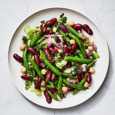Hearty Three-Bean Salad with crisp celery, red onion, and fresh parsley, tossed in a bright apple cider vinegar dressing.