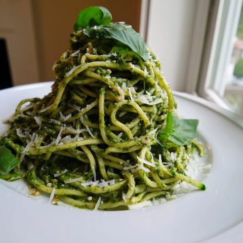 Freshly sautéed zucchini noodles with pesto, garnished with red pepper flakes and Parmesan, served as a light main dish.