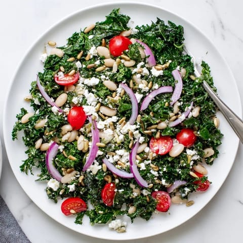 This Mediterranean White Bean and Kale Salad showcases massaged kale, white beans, red onion slices, and toasted sunflower seeds, ready to serve as a light lunch.  