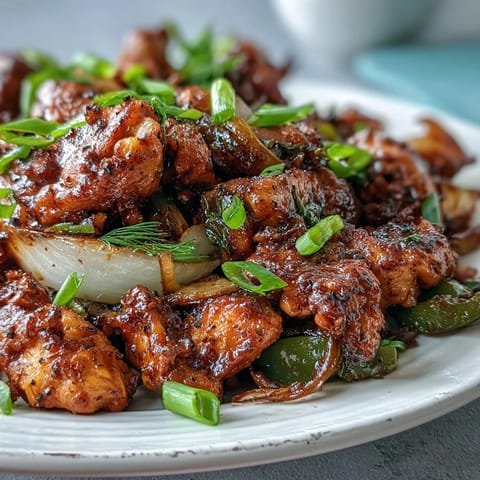 Boldly seasoned Black Pepper Chicken served over steamed white rice, garnished with fresh green onions.