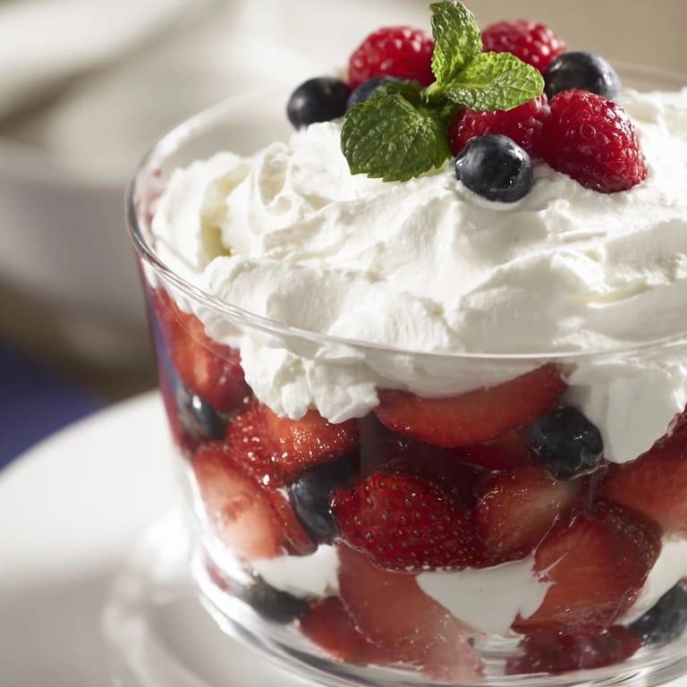 Enjoy a layered berry parfait: a delightful dessert with fresh berries and perfectly sweetened whipped cream.