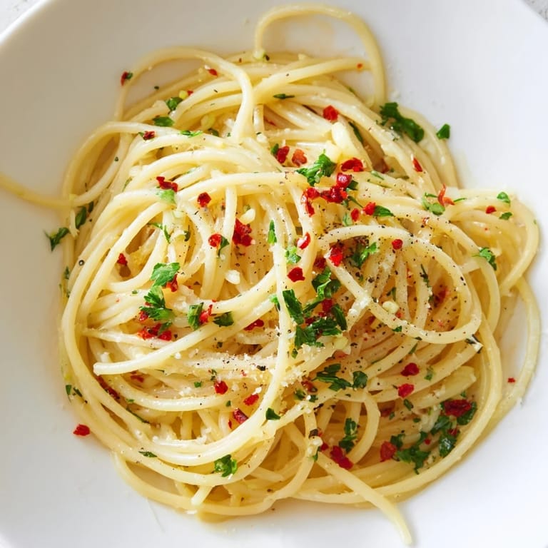 Close-up of golden Aglio e Olio Express Pasta, beautifully plated with grated Parmesan and chili flakes.