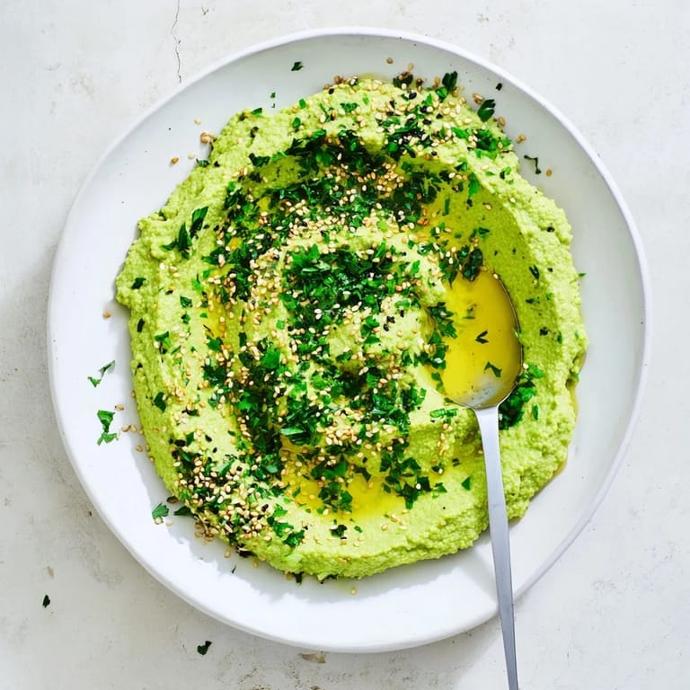 Smooth Edamame Hummus garnished with parsley and sesame, ideal for spreading on sandwiches or scooping with crunchy vegetables.