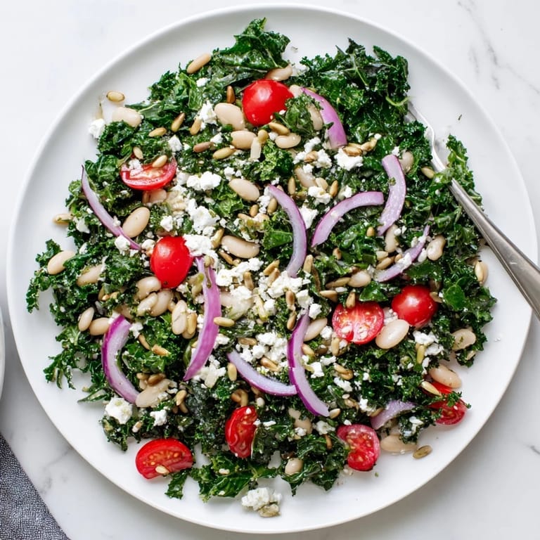 This Mediterranean White Bean and Kale Salad showcases massaged kale, white beans, red onion slices, and toasted sunflower seeds, ready to serve as a light lunch.  