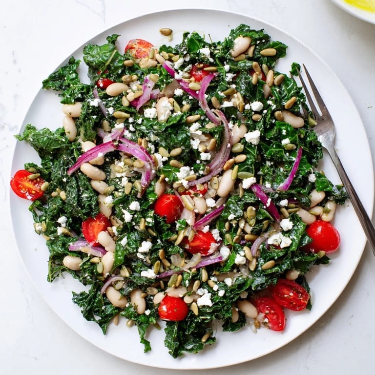 Enjoy a hearty White Bean and Kale Salad with tender kale, creamy beans, cherry tomatoes, and a zesty lemon dressing, topped with optional feta and seeds.