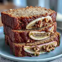 A slice of moist banana bread topped with Greek yogurt and fresh berries, perfect for a protein-rich breakfast.